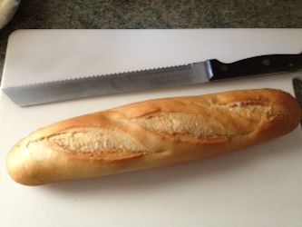 Baguette and bread knife on board Baguette and bread knife on board